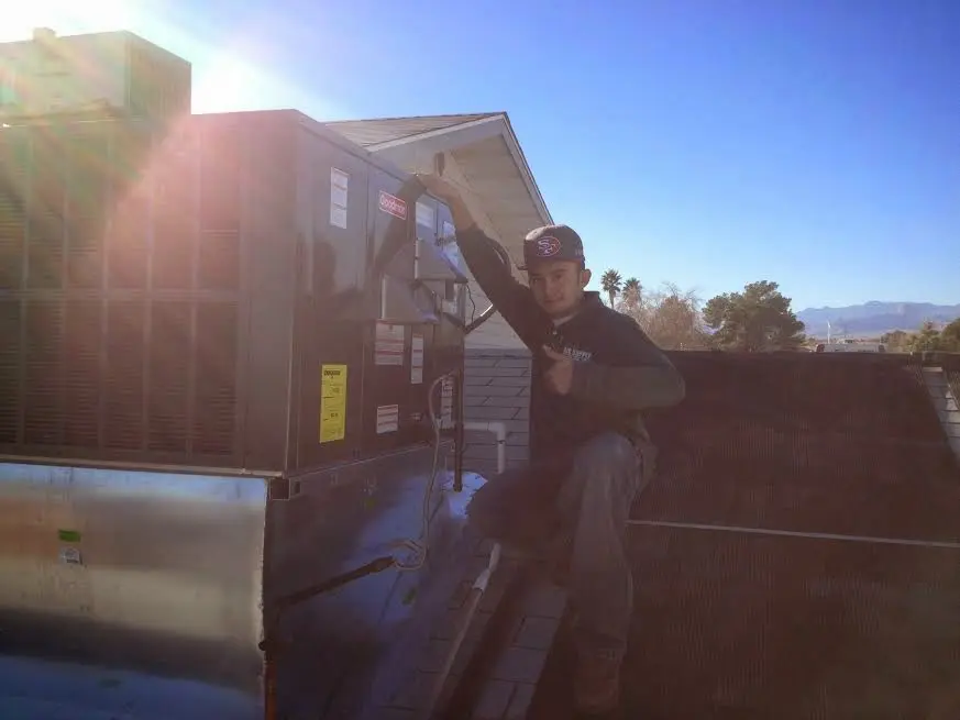HVAC technician performing Air Duct Repair on a rooftop unit in On Top of the World